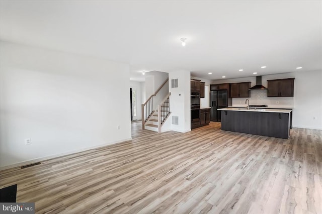 unfurnished living room featuring stairway, light wood-style floors, and visible vents