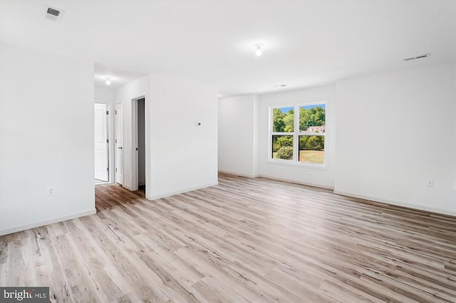 empty room with visible vents, baseboards, and wood finished floors