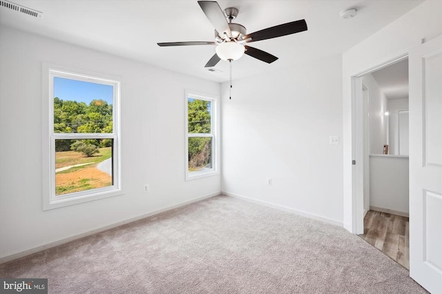 carpeted empty room featuring visible vents, baseboards, and ceiling fan