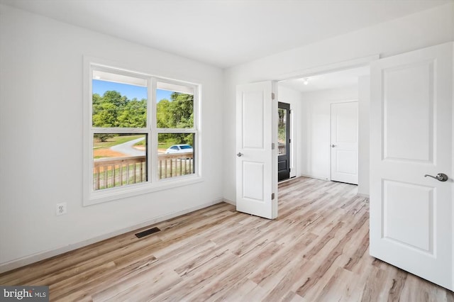 spare room featuring baseboards, visible vents, and light wood finished floors