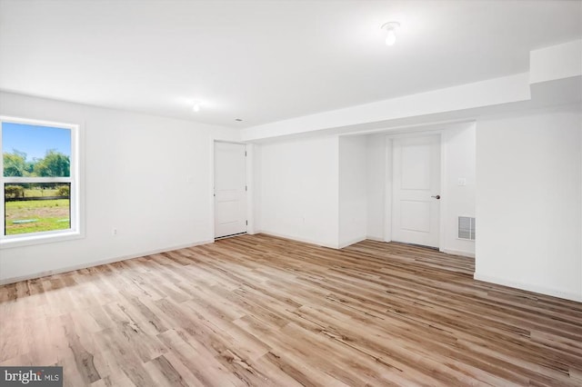 empty room featuring wood finished floors, visible vents, and baseboards