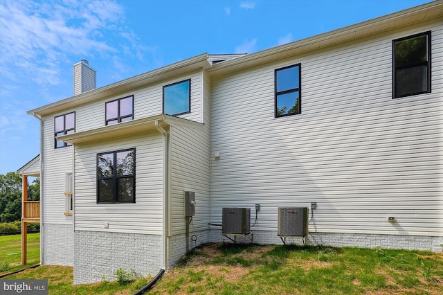 back of property featuring a yard, central AC unit, and a chimney