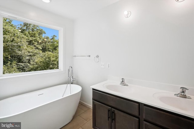 bathroom with tile patterned flooring, a freestanding tub, double vanity, and a sink