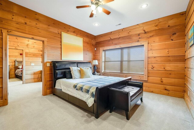 bedroom with ceiling fan, light colored carpet, and wooden walls