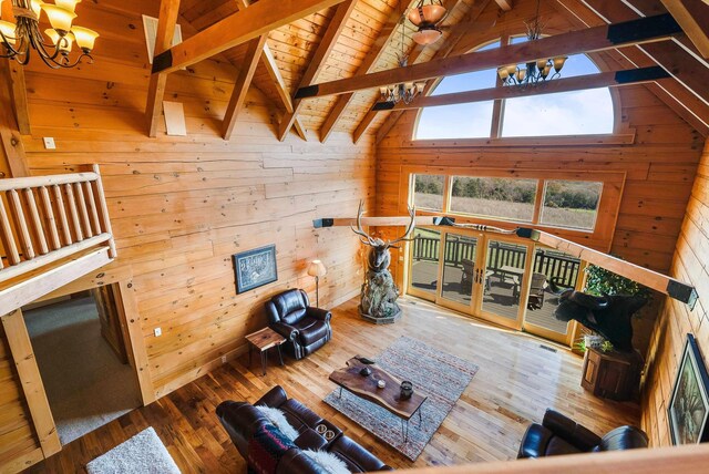 living room with an inviting chandelier, beam ceiling, hardwood / wood-style flooring, and wood walls