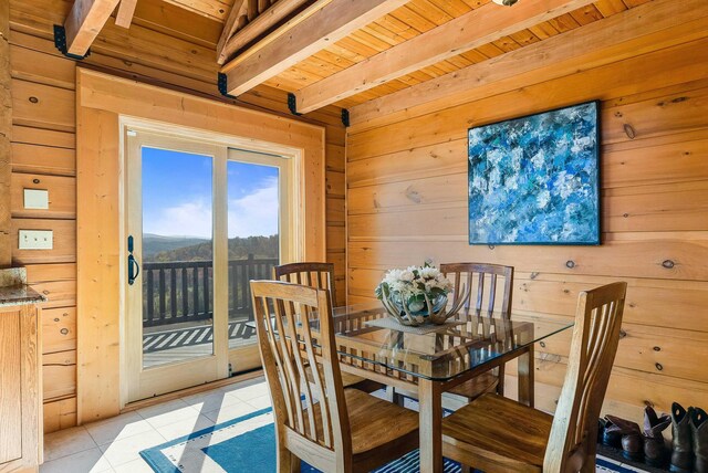 dining space with beam ceiling, light tile patterned floors, and wooden walls