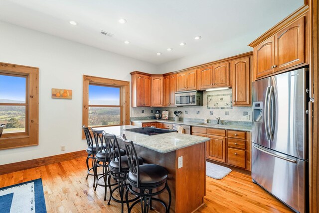 kitchen featuring a kitchen island, tasteful backsplash, sink, a kitchen breakfast bar, and stainless steel appliances