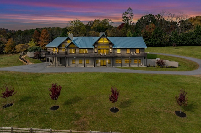 back house at dusk featuring a wooden deck and a yard