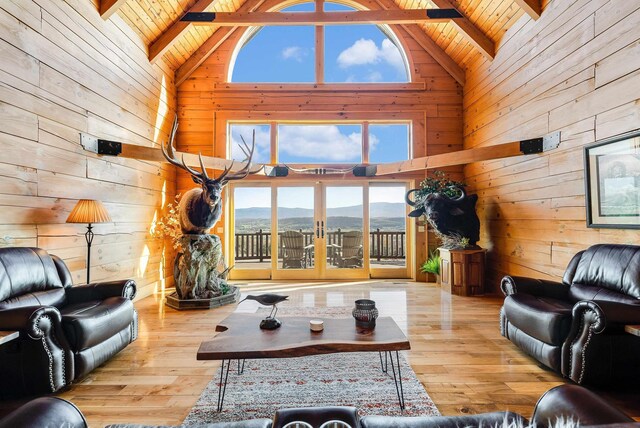 living room with beamed ceiling, wood ceiling, a mountain view, and wood walls