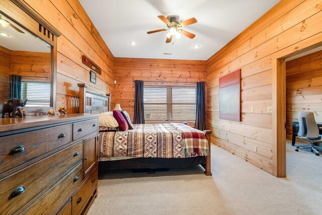 carpeted bedroom featuring ceiling fan and wood walls