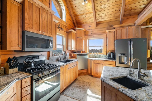 kitchen featuring light stone countertops, appliances with stainless steel finishes, sink, and light tile patterned flooring