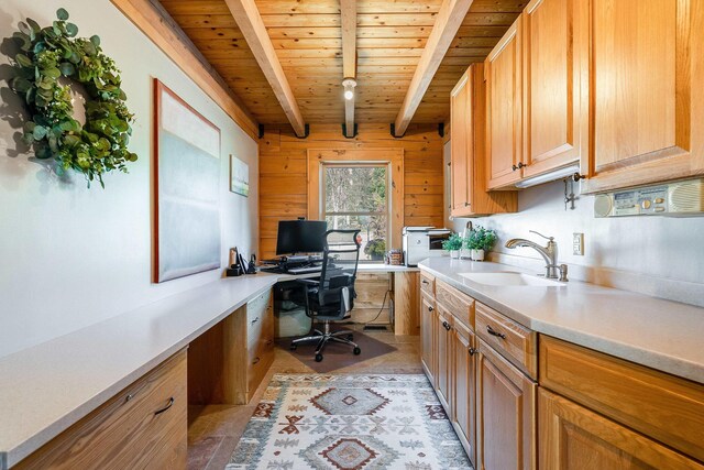 home office with built in desk, wood walls, beamed ceiling, sink, and wood ceiling