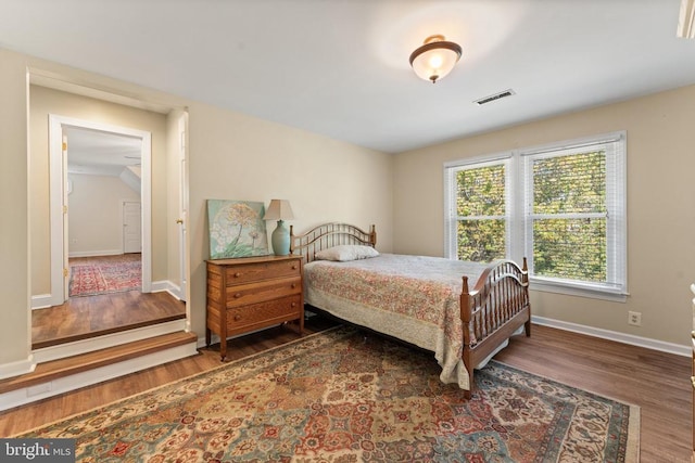 bedroom with vaulted ceiling, wood finished floors, visible vents, and baseboards