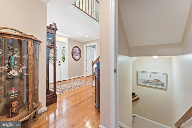 entryway featuring ornamental molding, stairway, wood finished floors, and baseboards