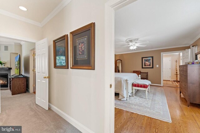 corridor with ornamental molding, light wood-style floors, and baseboards