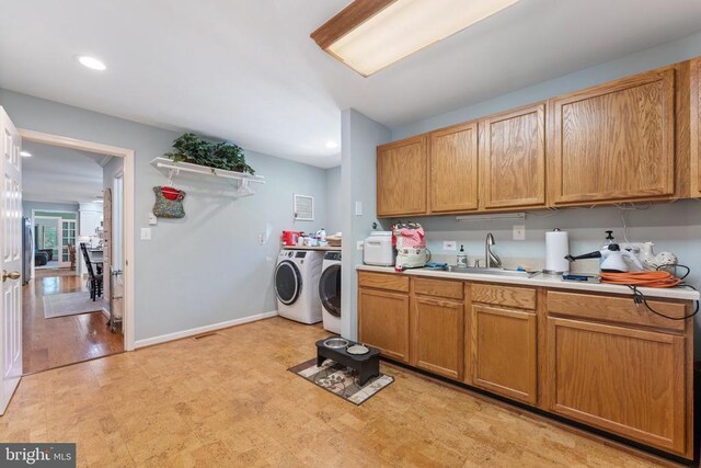 kitchen featuring recessed lighting, light countertops, a sink, washer and dryer, and baseboards