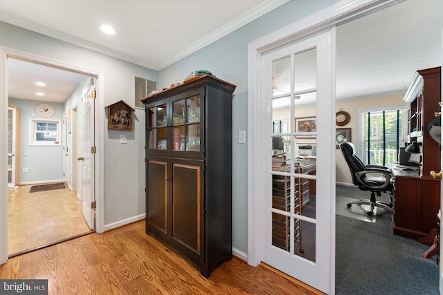 interior space with light wood-type flooring, crown molding, and baseboards