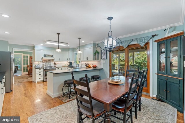 dining area featuring ornamental molding, light wood finished floors, and recessed lighting