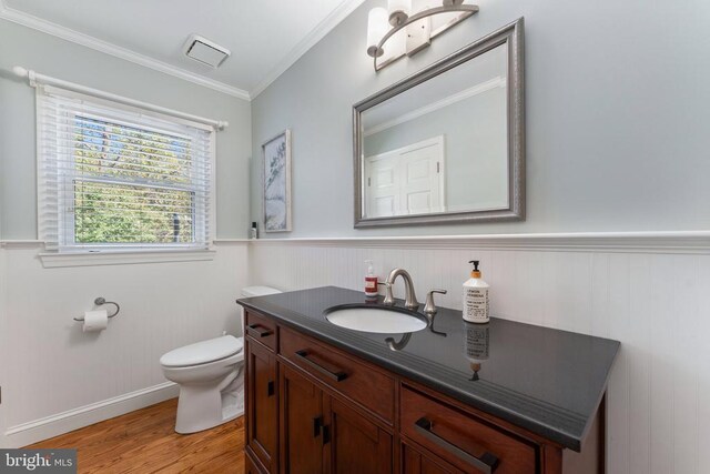 half bath featuring vanity, wainscoting, wood finished floors, and toilet