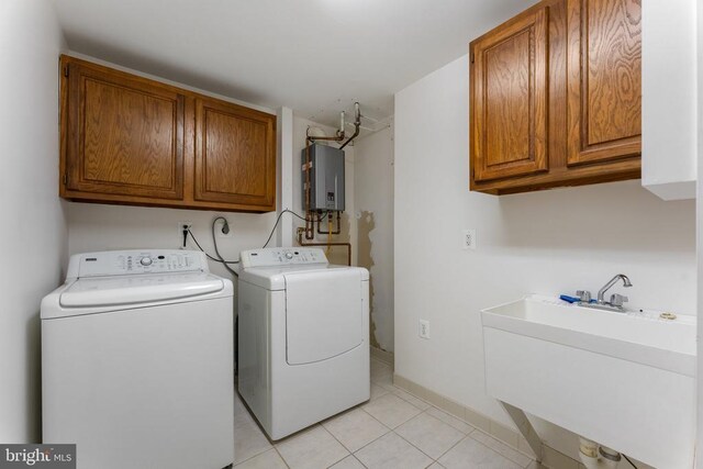 washroom featuring light tile patterned floors, a sink, washer and dryer, water heater, and cabinet space