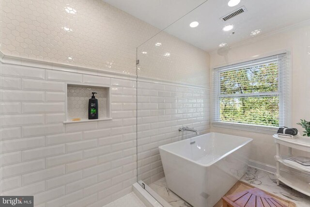 full bath featuring visible vents, marble finish floor, a freestanding tub, tile walls, and recessed lighting