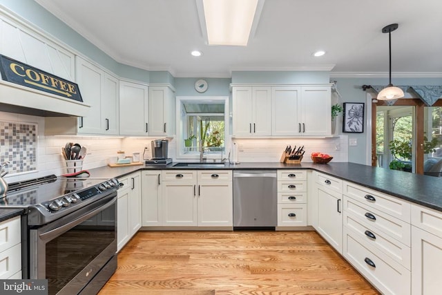 kitchen with crown molding, stainless steel appliances, dark countertops, light wood-style floors, and a sink