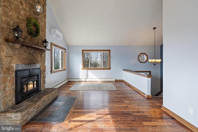 unfurnished living room featuring dark wood-type flooring, baseboard heating, a wall unit AC, a notable chandelier, and a stone fireplace