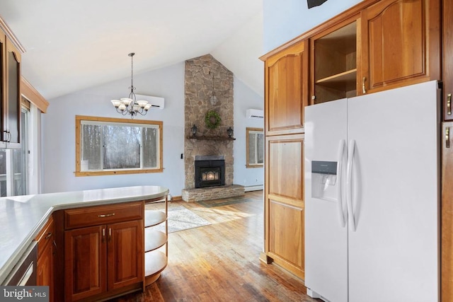 kitchen featuring a stone fireplace, hardwood / wood-style floors, pendant lighting, lofted ceiling, and white refrigerator with ice dispenser