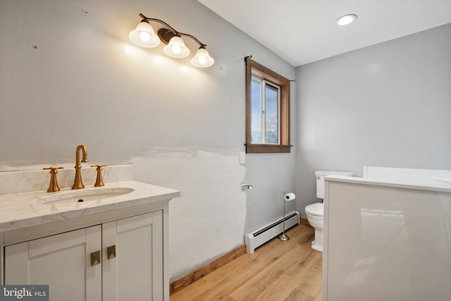 bathroom with a baseboard radiator, wood-type flooring, vanity, and toilet