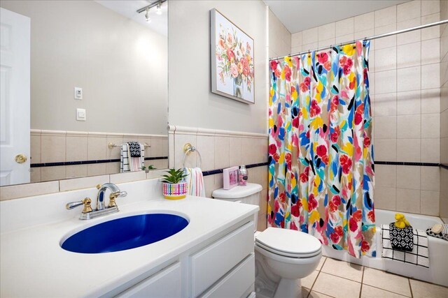 full bathroom with shower / tub combo with curtain, tile walls, vanity, tile patterned floors, and toilet