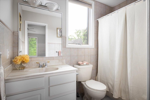 bathroom with a shower with curtain, vanity, tile walls, and toilet