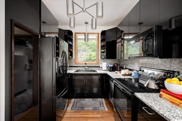 kitchen with sink, decorative backsplash, hanging light fixtures, black appliances, and light stone countertops