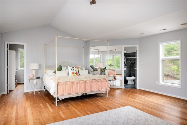 bedroom featuring hardwood / wood-style flooring, vaulted ceiling, and ensuite bath