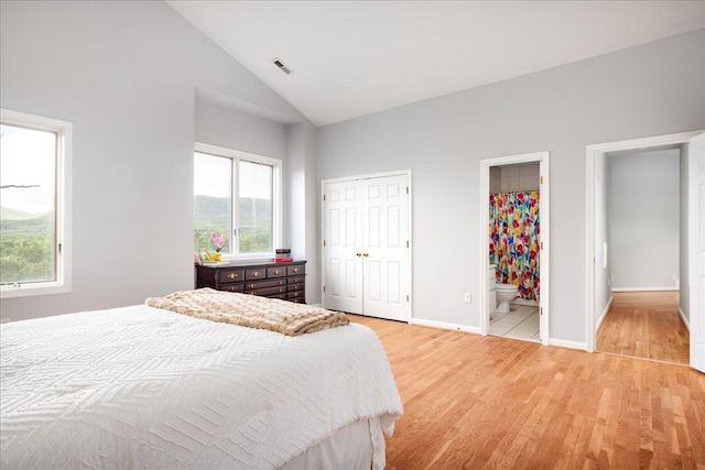 bedroom featuring high vaulted ceiling, light hardwood / wood-style floors, and ensuite bathroom