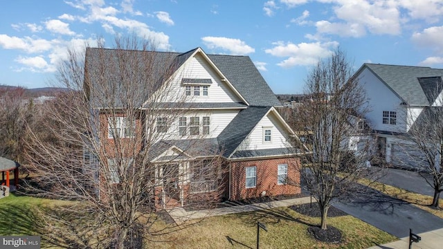 shingle-style home with brick siding and a front lawn