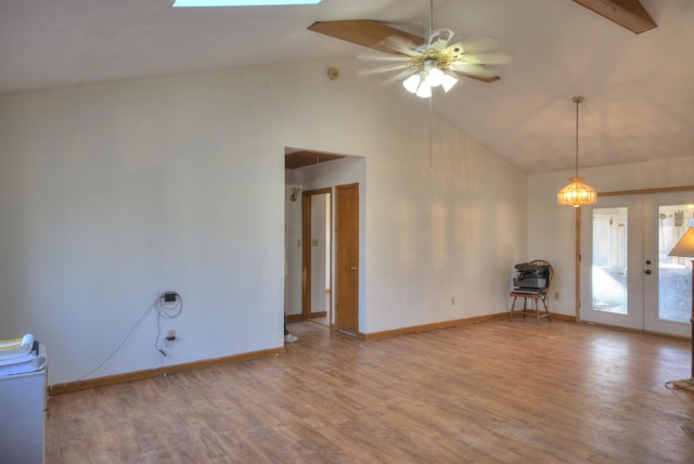 unfurnished room with hardwood / wood-style flooring, ceiling fan, a skylight, high vaulted ceiling, and french doors