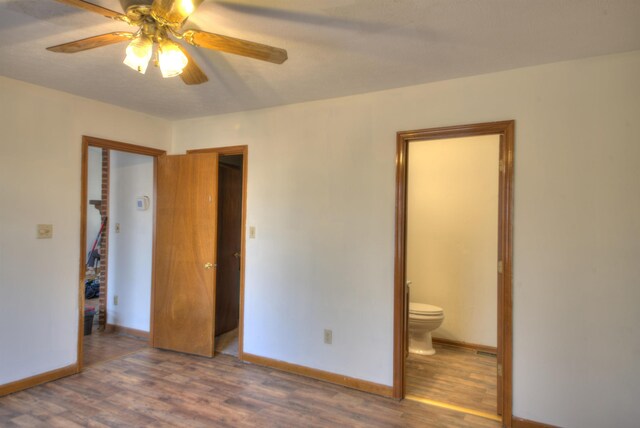 unfurnished bedroom featuring dark hardwood / wood-style flooring, connected bathroom, and ceiling fan