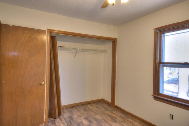 unfurnished bedroom with dark wood-type flooring, a closet, and ceiling fan