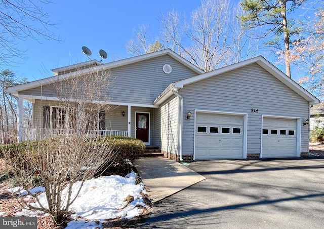 view of front of house featuring aphalt driveway, covered porch, and an attached garage