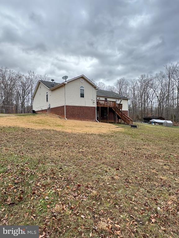 view of side of property with a deck, a lawn, and stairway