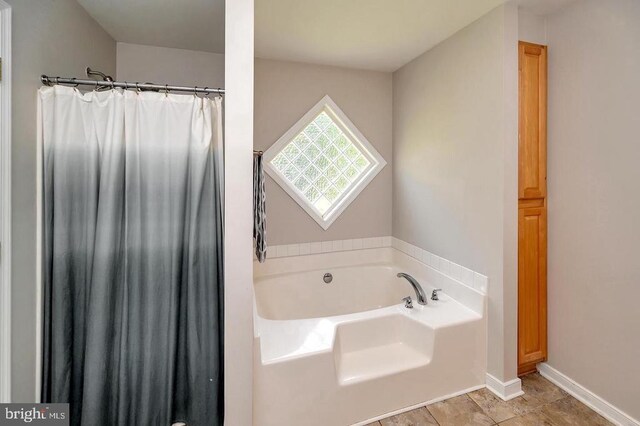 bathroom featuring a garden tub and baseboards