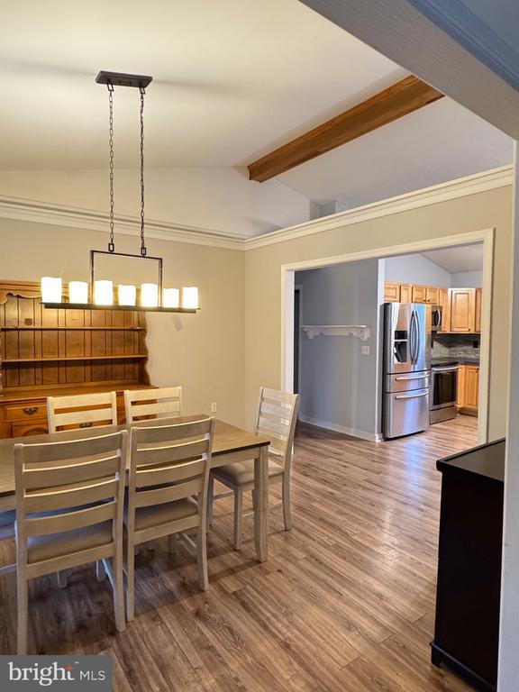 dining area featuring lofted ceiling with beams, crown molding, and wood finished floors