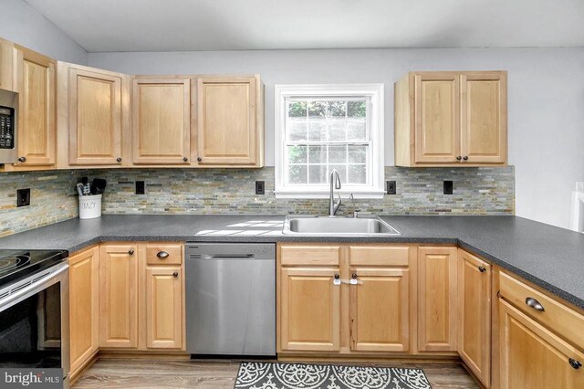 kitchen with stainless steel appliances, dark countertops, a sink, and tasteful backsplash