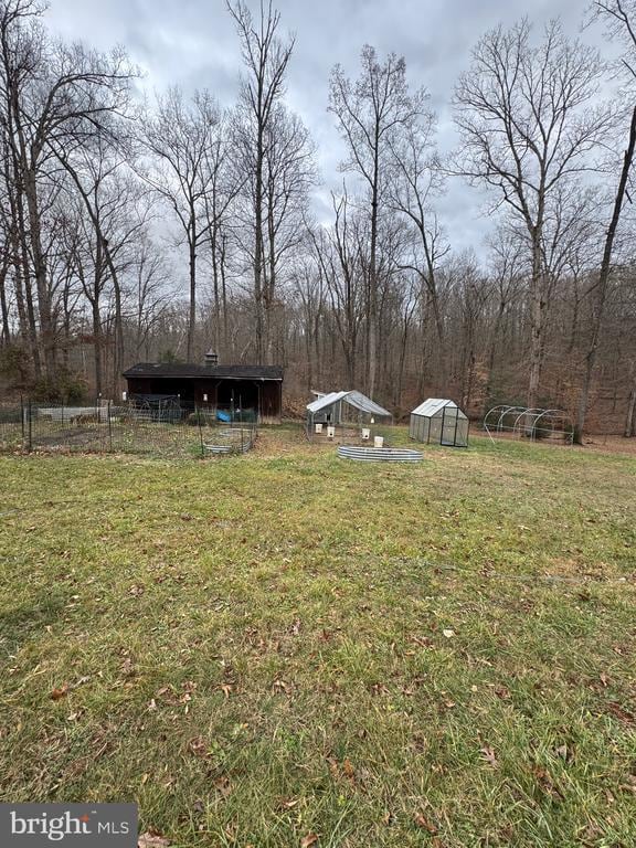 view of yard featuring fence, an exterior structure, and an outbuilding