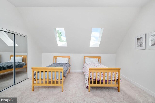 bedroom with vaulted ceiling with skylight, light colored carpet, and a closet