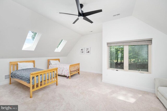 bedroom with light carpet, ceiling fan, and vaulted ceiling with skylight