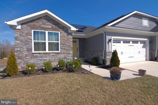 view of front of home with solar panels, concrete driveway, a front yard, a garage, and stone siding