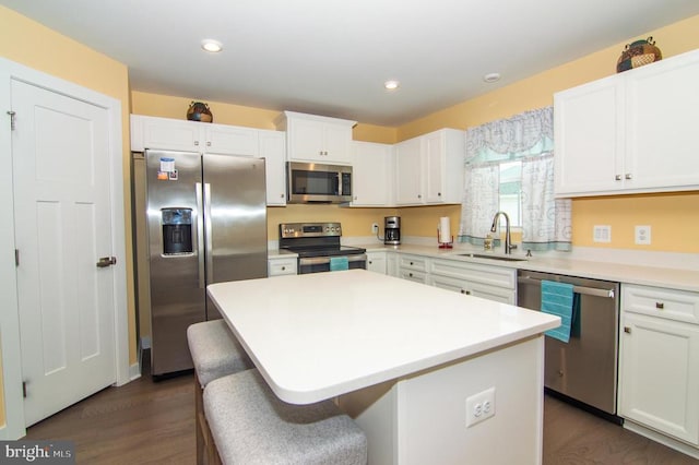 kitchen with white cabinets, a center island, light countertops, stainless steel appliances, and a sink