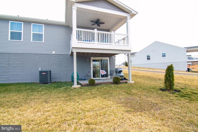 back of property featuring central AC unit, a balcony, brick siding, a ceiling fan, and a lawn