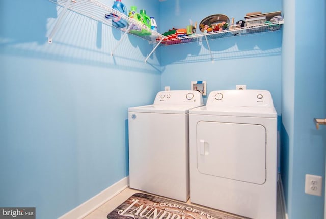 washroom featuring washer and dryer, laundry area, tile patterned flooring, and baseboards